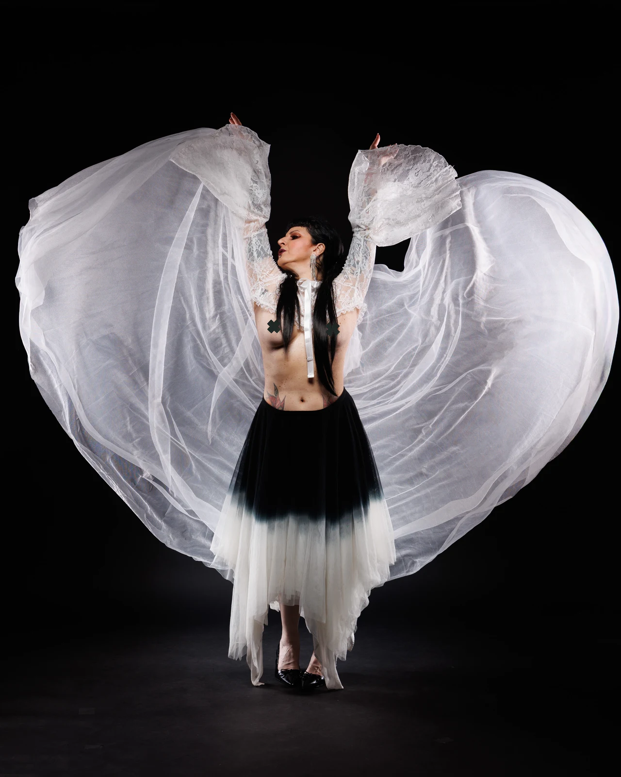 Anaïs Lune lifting flowing white fabric against a black backdrop