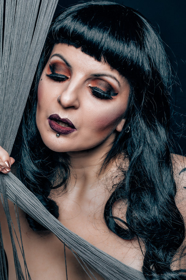 Anaïs Lune resting against sheer fabric, dark lipstick