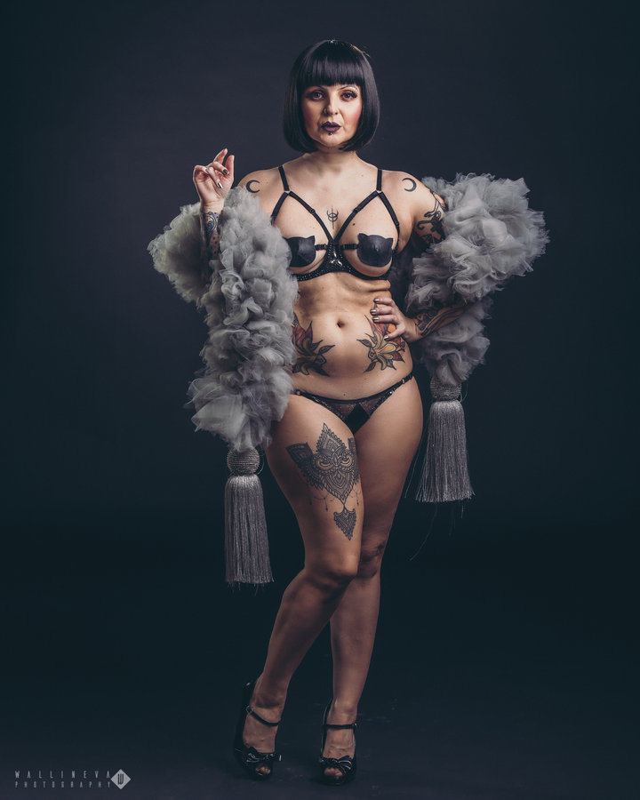 Anaïs Lune in black lingerie holding a grey feather boa