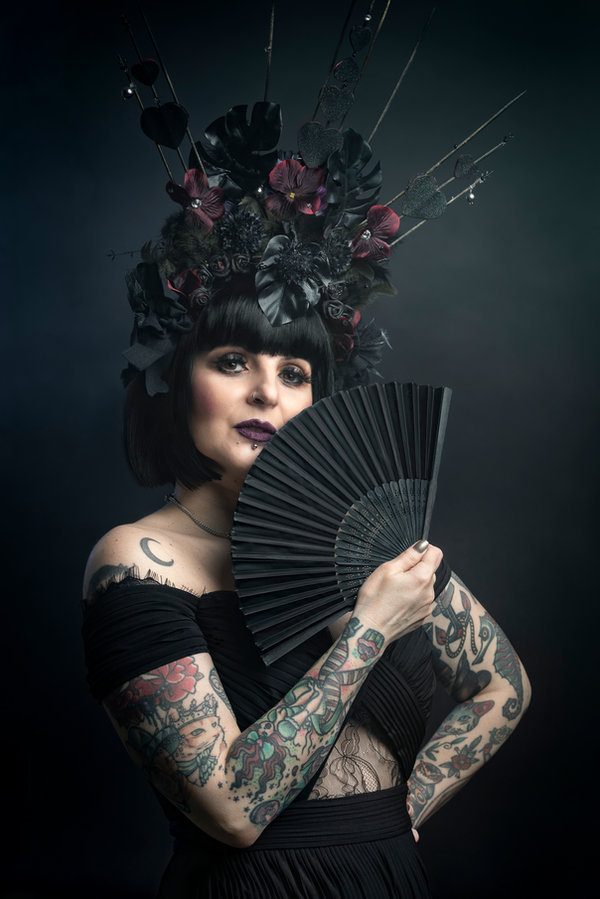 Anaïs Lune holding a black folding fan, ornate headpiece