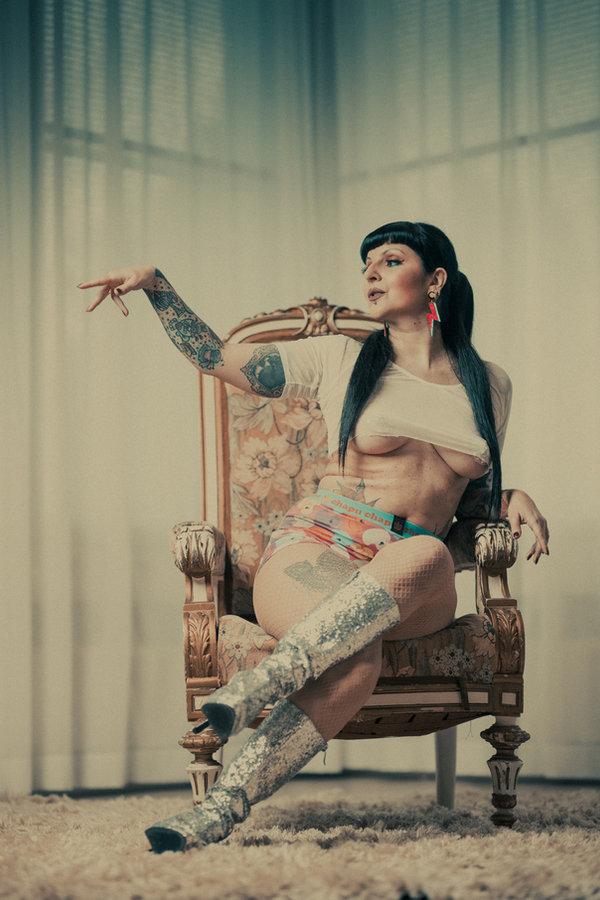 Anaïs Lune on an ornate wooden armchair near sheer curtains