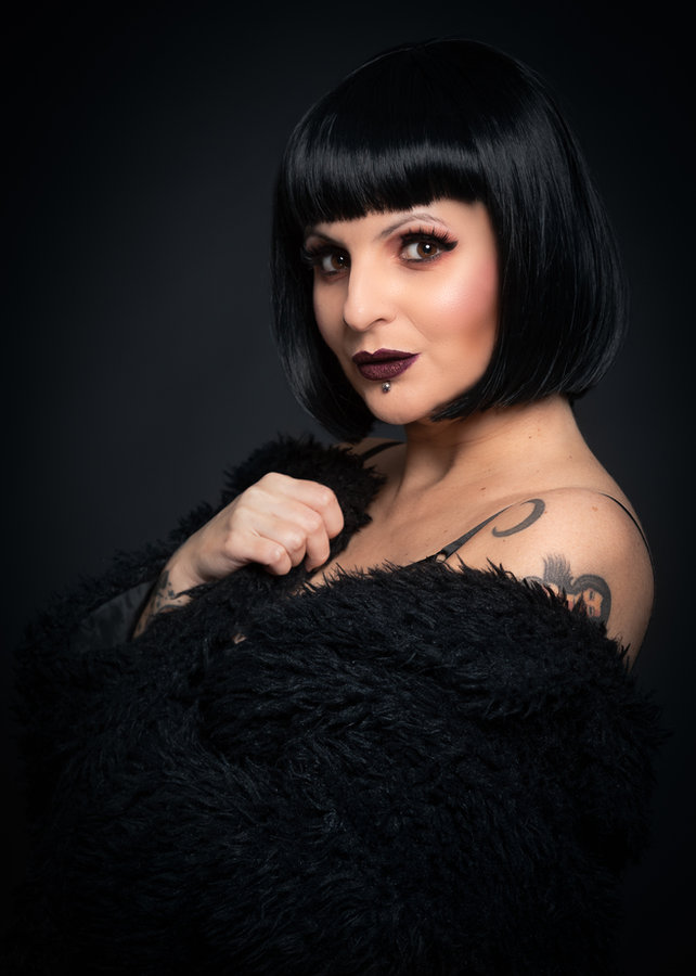 Anaïs Lune wrapped in black knitwear, dark moody light