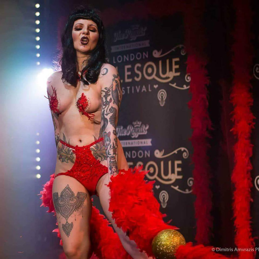 Anaïs Lune in red lingerie and floral pasties holding a feather boa on the London Burlesque Festival stage