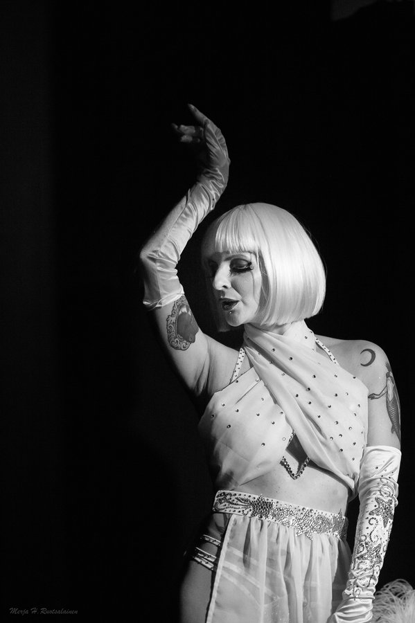Black-and-white photo of Anaïs Lune in a blonde bob raising a gloved arm